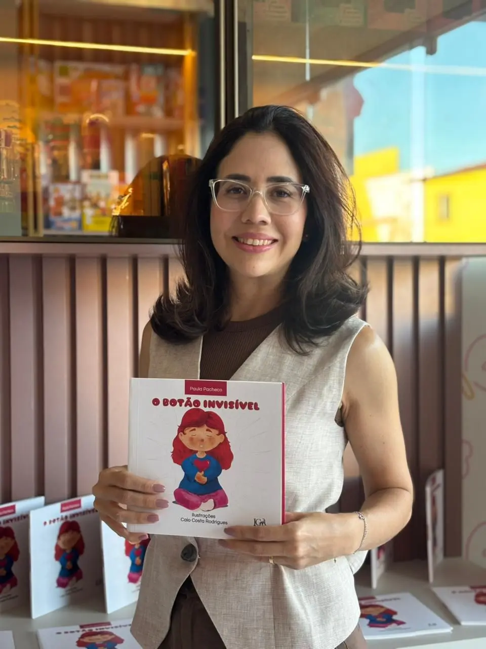 Foto da Doutora Paula segurando o livro 'O Botão Invisível'