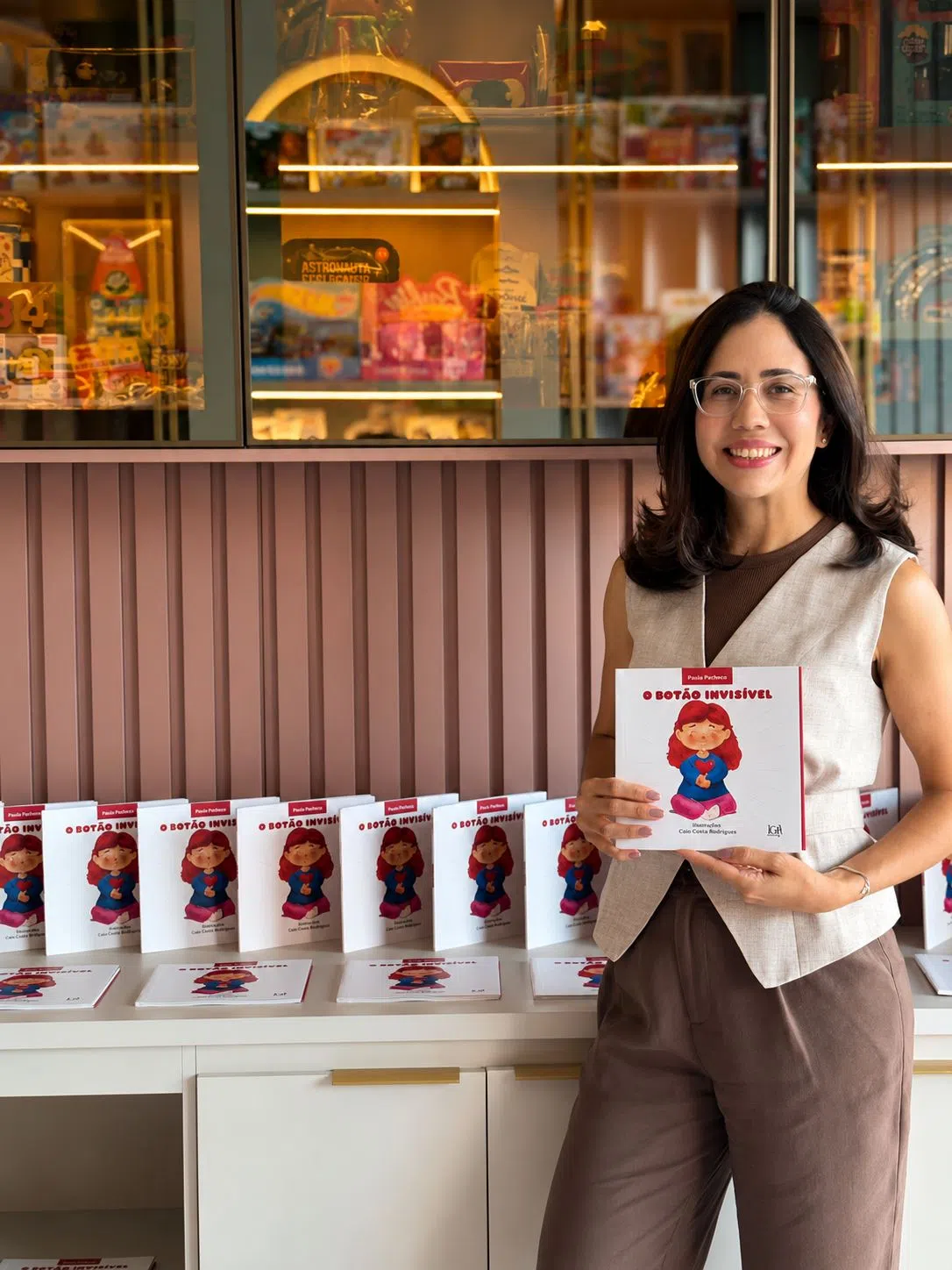 Foto da Doutora Paula segurando o livro 'O Botão Invisível'